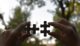 A person holding two pieces of a puzzle photo