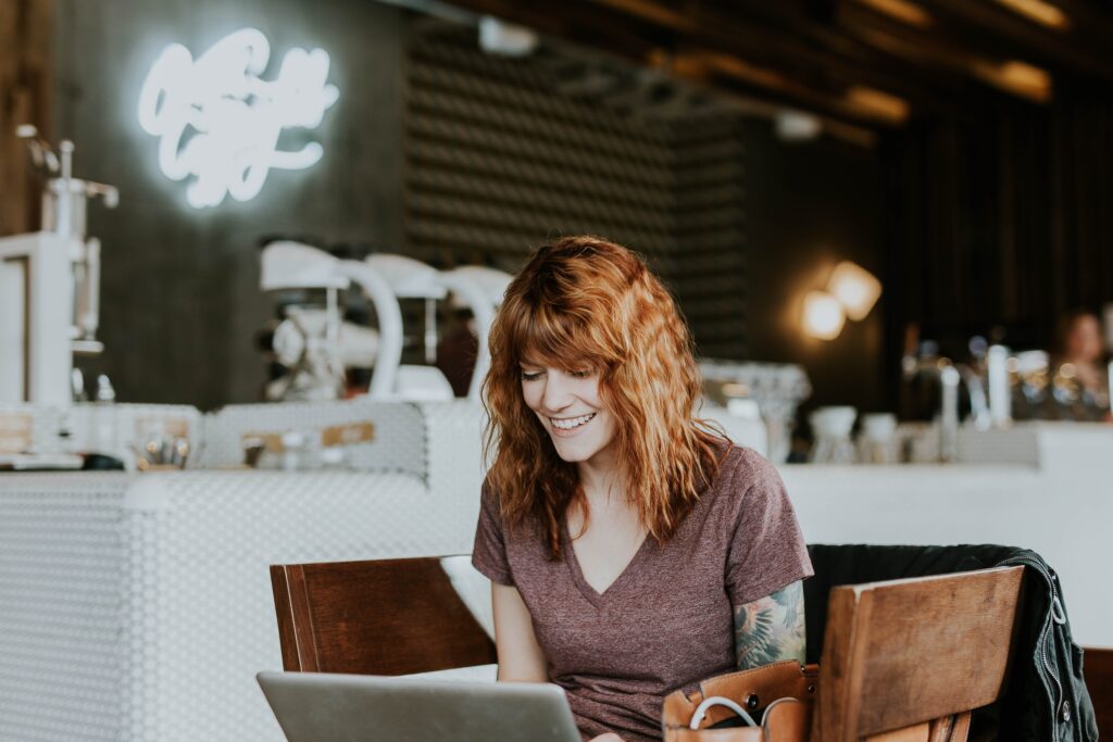 Woman sitting on brown wooden chair while using silver laptop